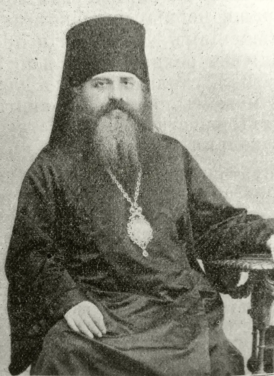 Чёрно-белый портрет архиерея средних лет в клобуке, с окладистой бородой и панагией на груди, сидящего в кресле