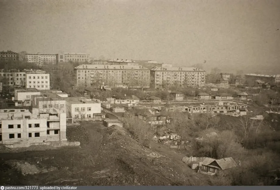 Чёрно-белая панорама жилого района с многоэтажками, ветхими деревянными домами и стройплощадкой на переднем плане