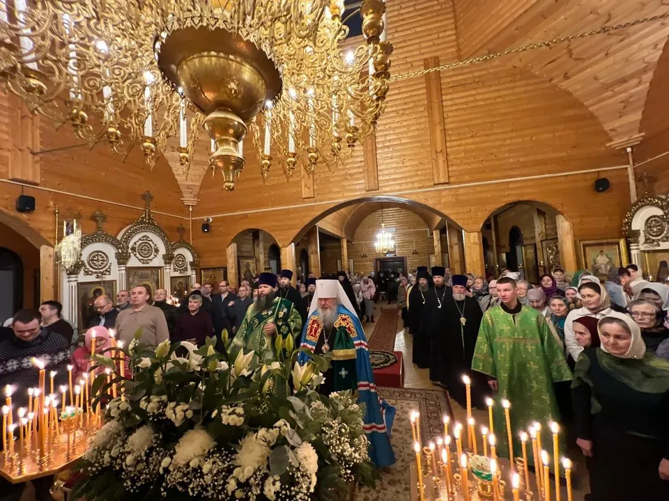 Митрополит Филарет у аналоя с цветами и свечами под паникадилом, вокруг — духовенство и множество прихожан